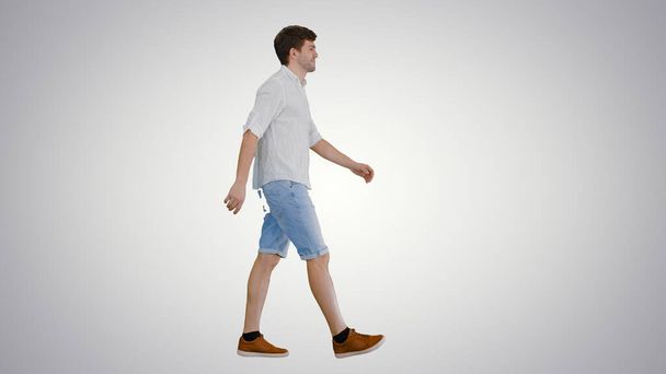 Casual young man walking and looking forward on gradient backgro - 写真・画像