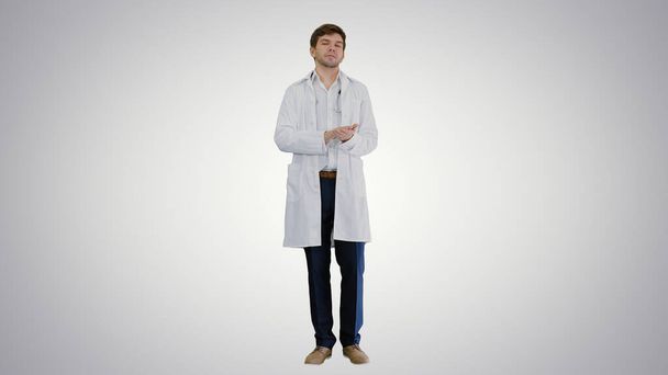 Male doctor talking to camera explaining something on gradient b - Foto, afbeelding