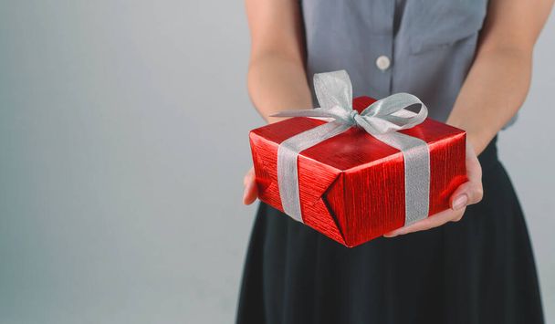 Červená dárková krabička se stuhou v ruce žena pro dávání v svátky nebo den oslav s kopií prostoru pro text. Koncept dovolené. - Fotografie, Obrázek
