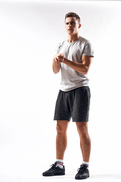 Un sportif en short et un t-shirt complet font des exercices sur un fond clair - Photo, image