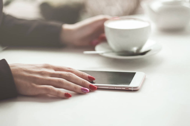 Woman hands with smart phone, headphones and cup of tea. For Graphic display montage - Photo, image