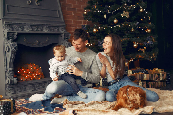 Family with cute dog at home near christmas tree - Фото, зображення
