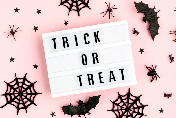 Halloween lapos laikus fénydoboz Trick vagy kezelni szöveg és dekoráció rózsaszín háttér. Ünnepi üdvözlőlap, party szórólap, meghívó koncepció - Fotó, kép