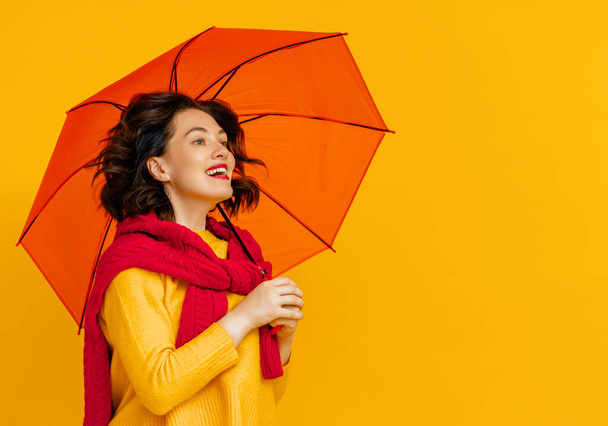 Happy emotional young woman with orange umbrella laughing  on color yellow background. - Foto, afbeelding