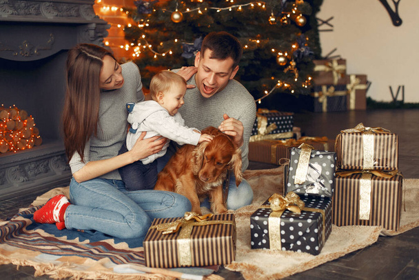 Family with cute dog at home near christmas tree - 写真・画像