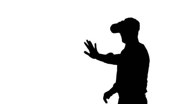 Silhouette Businessman in virtual reality headset walking in virtual world. - Photo, Image