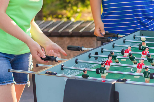 Cropped image of a girl and a young man who play table football while relaxing outdoors - Φωτογραφία, εικόνα