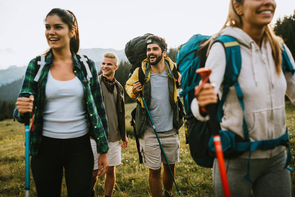 Group of friends trekking with backpacks walking outdoor - Фото, изображение