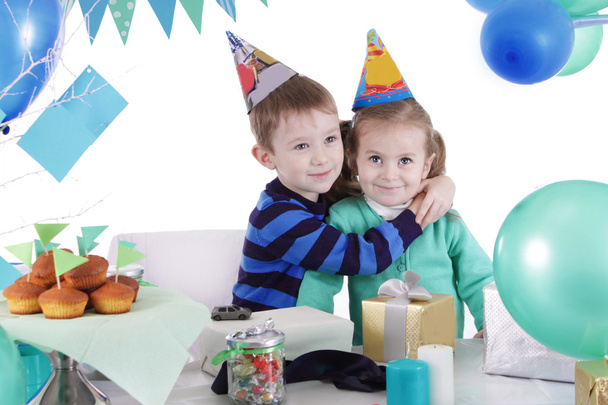Two children huging at blue party table - Foto, Bild