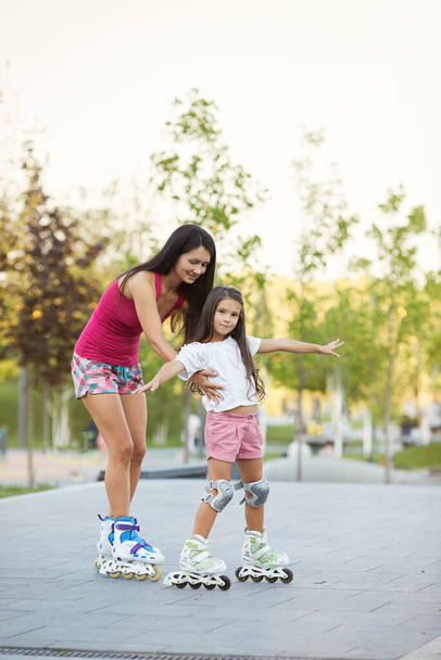 mother and her little daughter rollerskating - Foto, Imagem