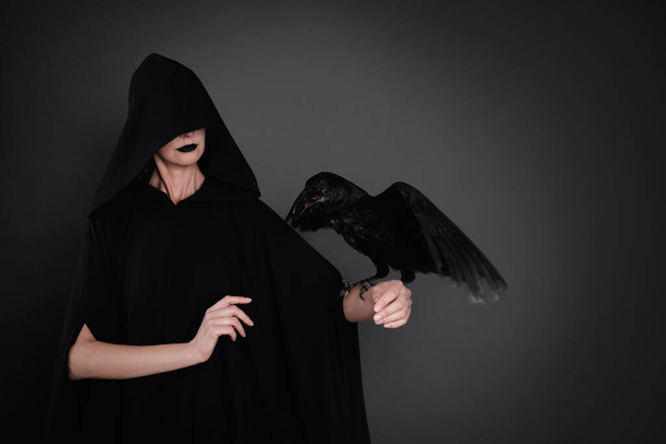Μυστηριώδης μάγισσα με κοράκι σε μαύρο φόντο - Φωτογραφία, εικόνα