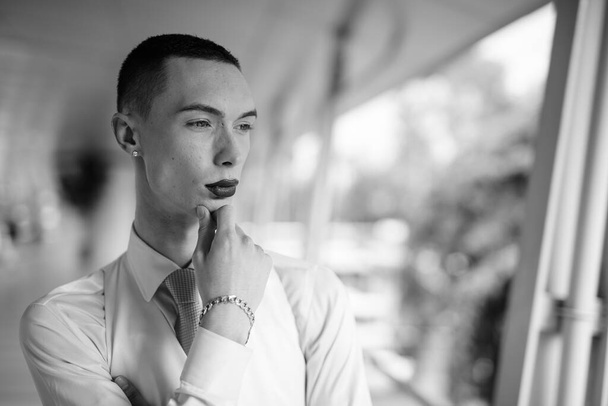 Retrato de jovem bonito empresário andrógino explorando ao redor da cidade em preto e branco - Foto, Imagem