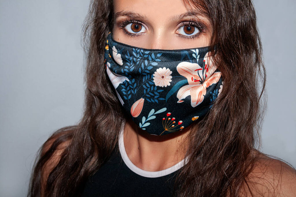 Großaufnahme einer verängstigten Frau, die eine schützende, selbstgemachte Gesichtsmaske als Schutz gegen Covid 19- Coronavirus, Infektionskrankheit trägt.  - Foto, Bild