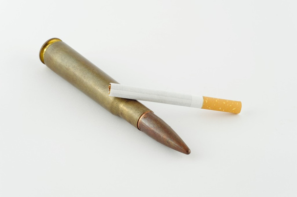 Cigarrillo y municiones sobre fondo blanco
 - Foto, Imagen