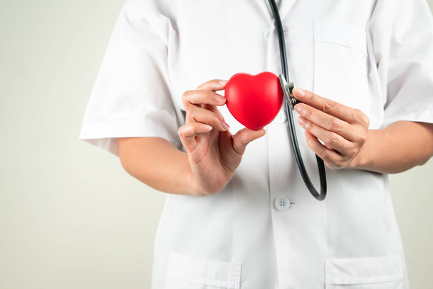 Παγκόσμια ημέρα της καρδιάς έννοια της γυναίκας γιατρός χέρι εκμετάλλευση κόκκινη καρδιά και στηθοσκόπιο - Φωτογραφία, εικόνα