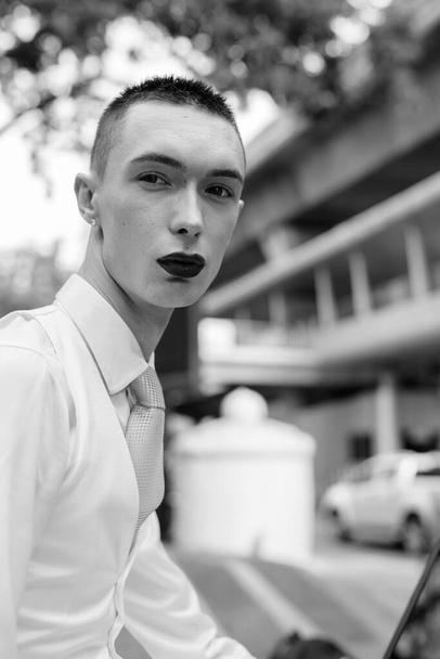 Πορτρέτο του νεαρού όμορφου ανδρόγυνου επιχειρηματία που εξερευνά γύρω από την πόλη σε μαύρο και άσπρο - Φωτογραφία, εικόνα