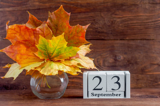 23 вересня за дерев'яним календарем і осіннім букетом з кленового кольору листя. дата осіннього місяця. Концепція Золота осінь
. - Фото, зображення