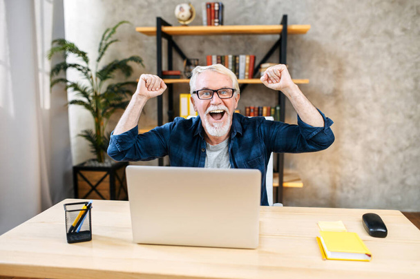 Older man is using laptop for working indoor - Foto, immagini