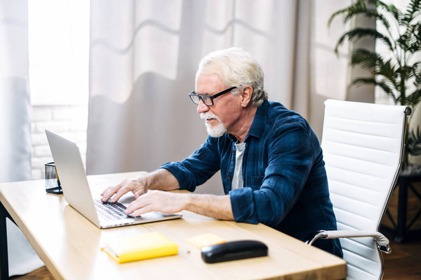 Older man is using laptop for working indoor - Zdjęcie, obraz