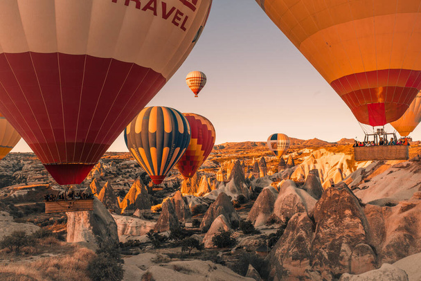 Cappadocia / Turkey - 14. září 2020: Létající horkovzdušné balóny a skalnatá krajina za úsvitu v Goreme, Cappadocia, Turecko - Fotografie, Obrázek