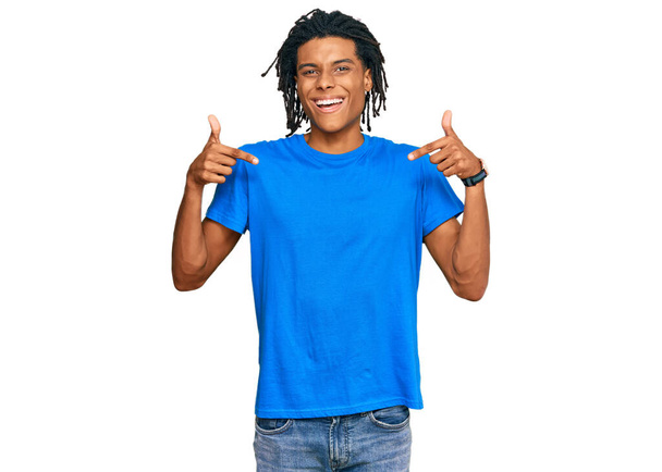 Fiatal afro-amerikai férfi alkalmi ruhát visel, magabiztos mosollyal az arcán, ujjaival büszkén és boldogan mutogat magára..  - Fotó, kép