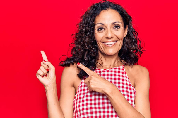 Middle age beautiful woman wearing casual sleeveless t shirt smiling and looking at the camera pointing with two hands and fingers to the side.  - Photo, Image