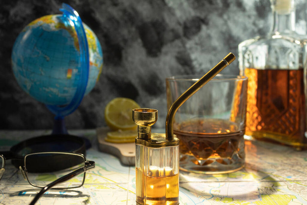 Globus mit einer Karte auf dem Tisch. Dekanter mit Cognac-Whiskey auf der Karte. Punkte und Lupe auf der Karte. - Foto, Bild