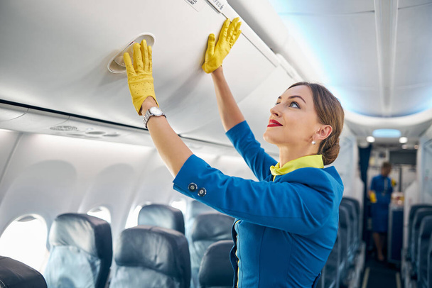 Charming air hostess learning closing compartment with hand luggage - Foto, Imagen