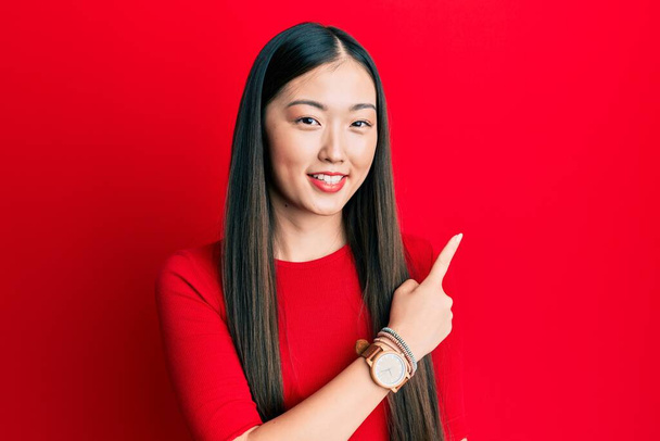 Young chinese woman wearing casual clothes smiling cheerful pointing with hand and finger up to the side  - Foto, immagini