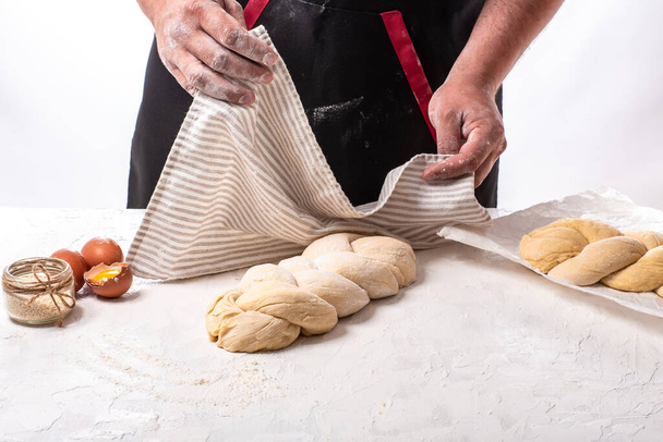 Het concept van de oosterse keuken. Nationaal Israël zelfgemaakt Rauwe challah traditioneel joods brood bedekt met linnen handdoek. - Foto, afbeelding
