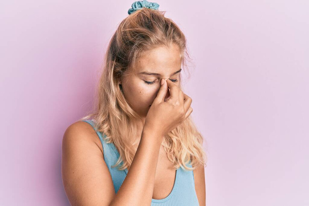 Young blonde girl wearing casual clothes tired rubbing nose and eyes feeling fatigue and headache. stress and frustration concept.  - Fotoğraf, Görsel