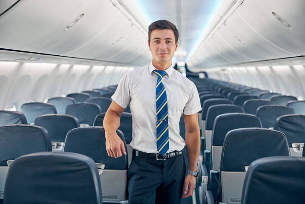 Junger Mann steht im leeren Bord eines Verkehrsflugzeugs - Foto, Bild