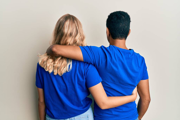 Joven pareja interracial vistiendo ropa casual abrazándose a uno mismo feliz y positivo desde atrás. amor propio y cuidado personal  - Foto, imagen