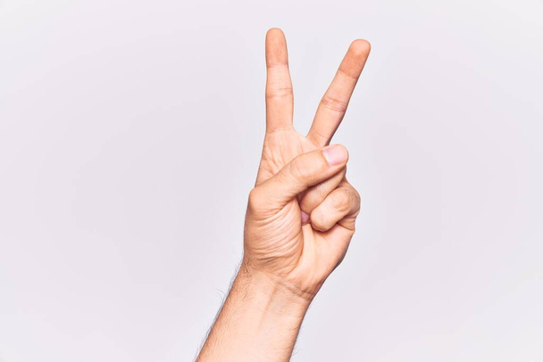 Blisko strony młodego człowieka kaukaskiego nad odizolowanym tle licząc numer 2 pokazuje dwa palce, gestykulując zwycięstwo i symbol zwycięzcy  - Zdjęcie, obraz