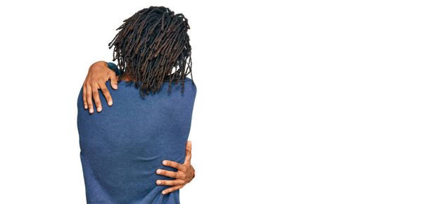 カジュアルな冬のセーターを着ている若いアフリカ系アメリカ人の男性は、後方から幸せと肯定的な抱擁。自己愛と自己ケア  - 写真・画像