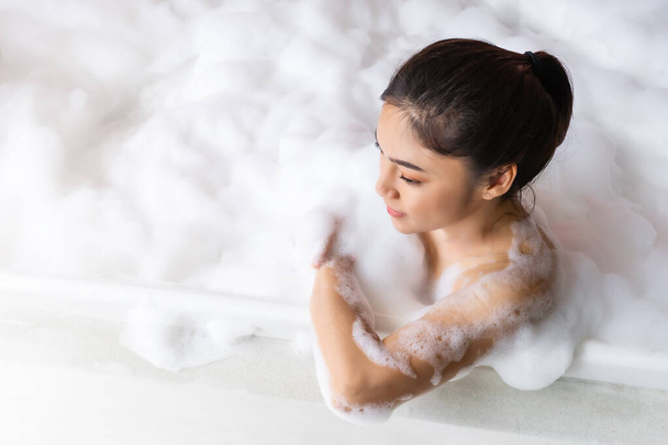 young woman relaxing and takes bubble bath in bathtub with foam - Fotó, kép