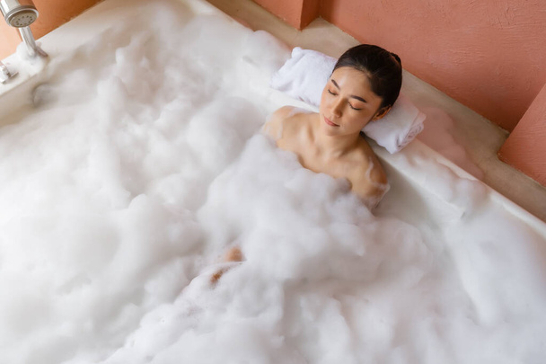 молода жінка розслабляється у ванні з закритими очима
  - Фото, зображення