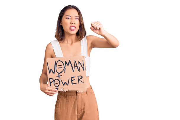 Молодая красивая китаянка, держащая в руках женское знамя власти, раздраженная и разочарованная, кричащая от гнева, кричащая сумасшедшая от злости и поднятая рука  - Фото, изображение