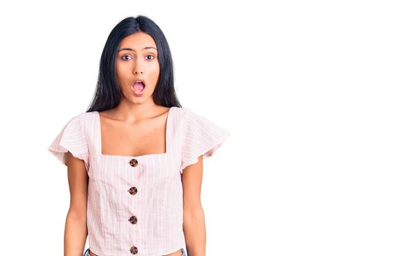Νέα όμορφη Λατίνα κοπέλα φορώντας casual ρούχα φοβάται και έκπληκτος με ανοιχτό το στόμα για έκπληξη, δυσπιστία πρόσωπο  - Φωτογραφία, εικόνα