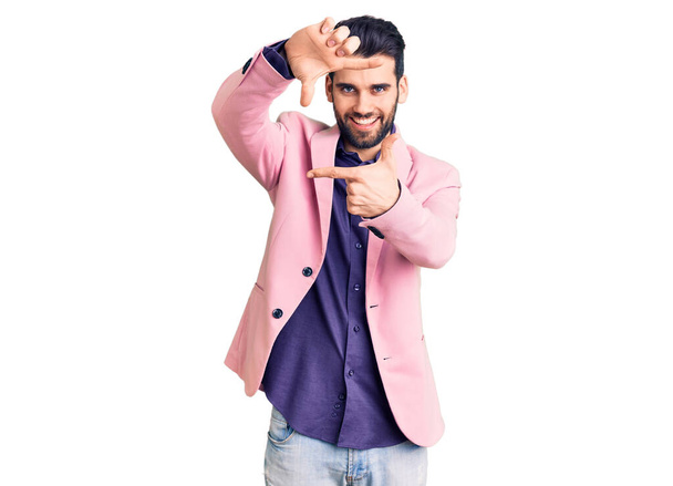 Young handsome man with beard wearing elegant jacket smiling making frame with hands and fingers with happy face. creativity and photography concept.  - Фото, изображение