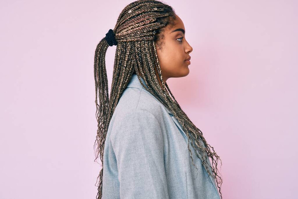 Young african american woman with braids wearing business jacket looking to side, relax profile pose with natural face with confident smile.  - Foto, afbeelding