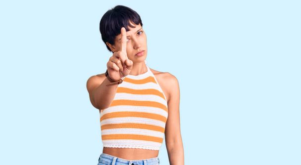 Young brunette woman with short hair wearing casual clothes pointing with finger up and angry expression, showing no gesture  - Photo, Image