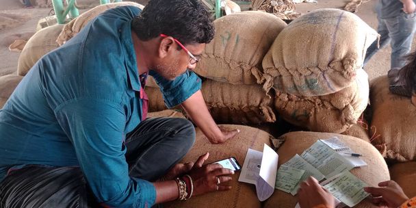 DISTRICT KATNI, INDIA - 18. KVĚTNA 2019: Indický vesnický zemědělec vypočítává na trhu se surovými potravinářskými obilovinami úrody. - Fotografie, Obrázek