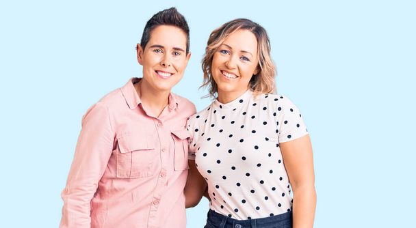 Couple de femmes portant des vêtements décontractés regardant positif et heureux debout et souriant avec un sourire confiant montrant les dents  - Photo, image