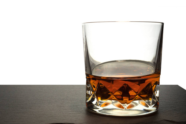 İzole bir arka planda bir bardak viski. Taş bir tahtanın üzerinde konyak - Fotoğraf, Görsel