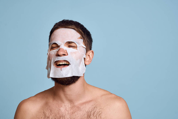 man in cleansing mask on blue background gesturing with hands naked torso cropped view - Foto, Imagen