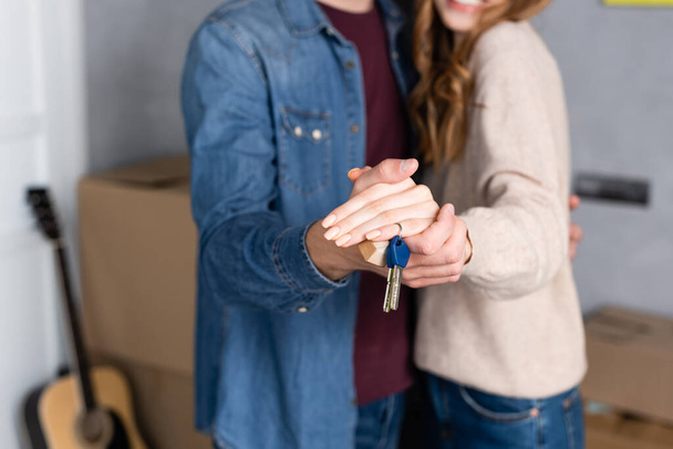 обрезанный вид мужчины и женщины, держащихся за руки и ключи, движущаяся концепция - Фото, изображение