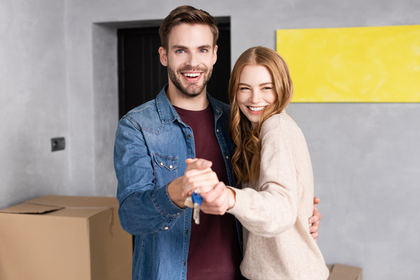 pleased man and woman holding hands and keys near box, moving concept - Фото, зображення
