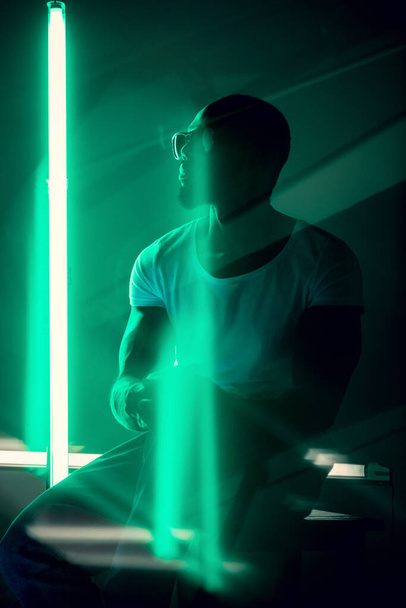 Cinematic portrait of handsome young man in neon lighted room, stylish musician - Fotoğraf, Görsel