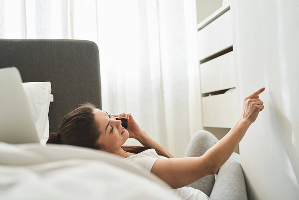 Woman with a gadget lying on the bed - Photo, Image
